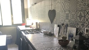 A kitchen with patterned tiles, a heart-shaped decoration, and a stove. - Large F2 in private residence (Ajaccio)