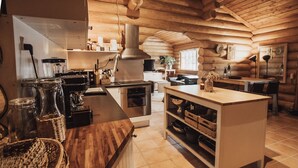A log cabin-style kitchen with wooden cabinets, a central island, and a stove.