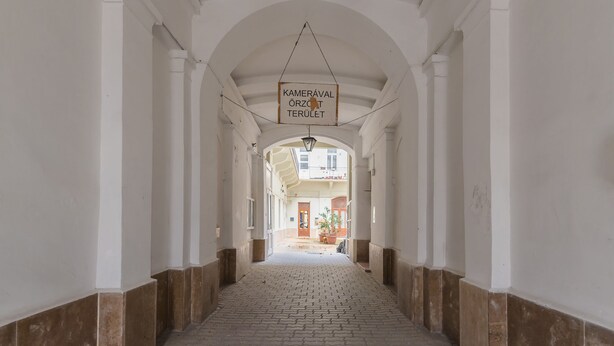 A corridor with white walls and a tiled floor, leading to a door at the end. - Siena Haven - Urban Suite (Budapest)