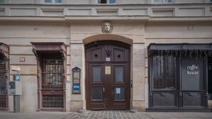 A building with a large, ornate entrance door marked with the number 21, a parking sign, and a coffee house sign. - Siena Haven - Urban Suite (Budapest)