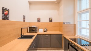 A modern kitchen with wooden countertops, a black sink, a microwave, a toaster, and a stove. - Siena Haven - Urban Suite (Budapest)