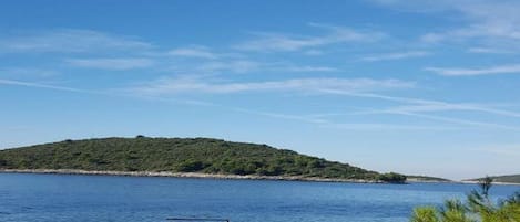 A coastal scene with a clear sky, calm water, and a small boat.