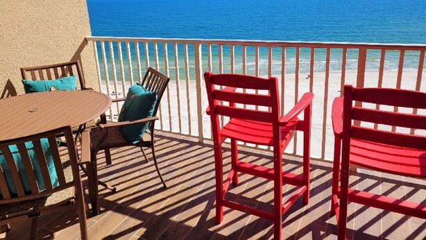 A balcony with a view of the ocean, featuring a table and two chairs. - Penthouse at Paradise 9th Floor (Orange Beach)