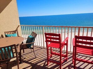 A balcony with a view of the ocean, featuring a table and two chairs. - Penthouse at Paradise 9th Floor (Orange Beach)