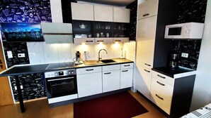 A modern kitchen with white cabinets, a black countertop, a built-in oven, and a microwave.