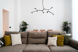 A modern living room with a sectional sofa, a dining table, and two potted plants.