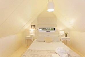 Une chambre à coucher avec un lit, des tables de chevet, une télévision et une fenêtre.