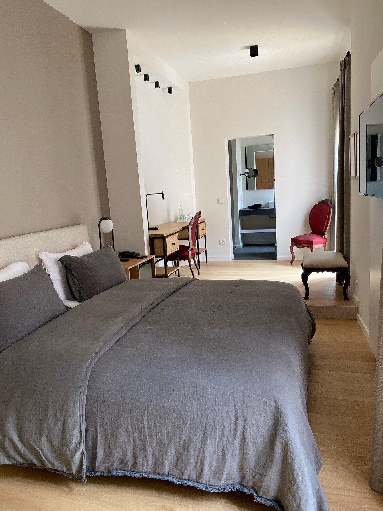 Ein Schlafzimmer mit einem großen Bett, einem Schreibtisch, einem Stuhl und einem Spiegel.