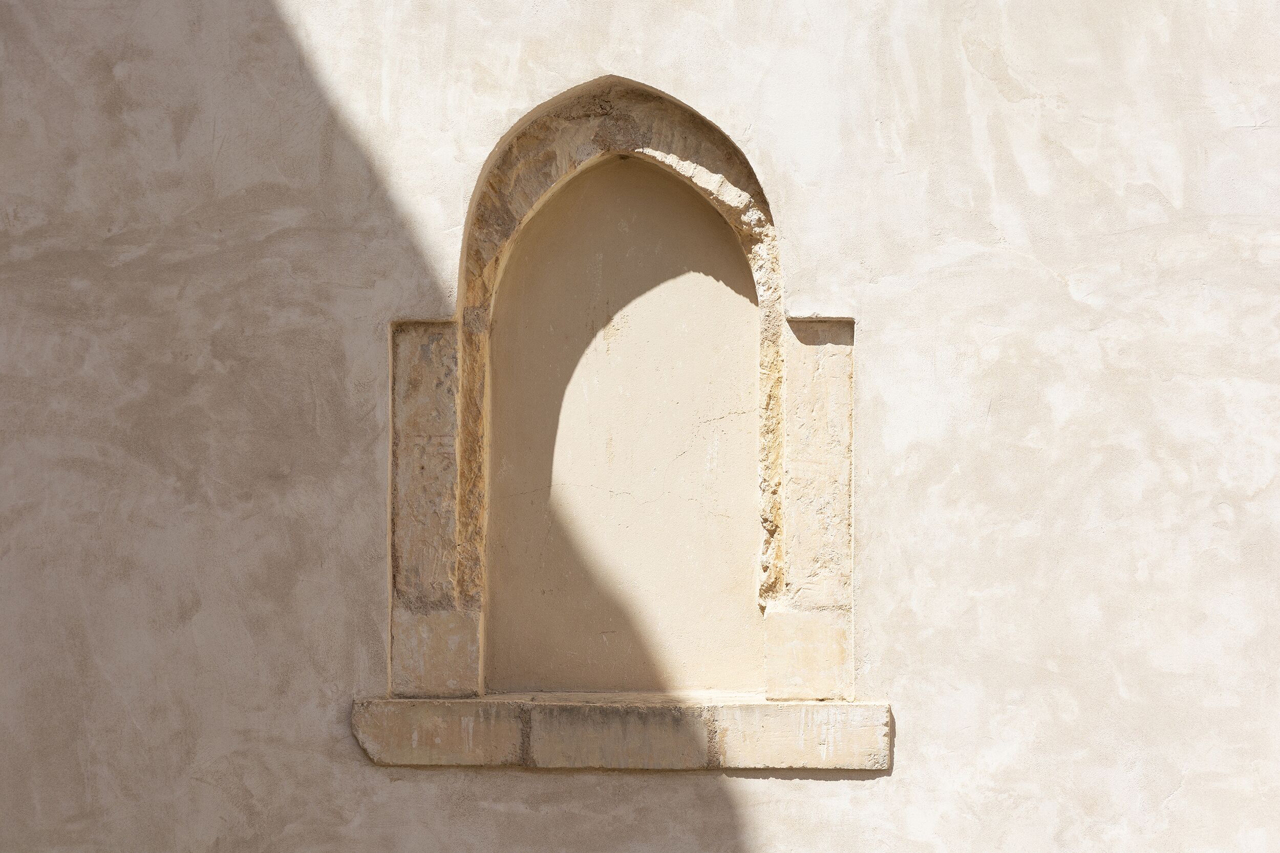 Une arche en pierre à la texture rugueuse et à la surface érodée par les intempéries.