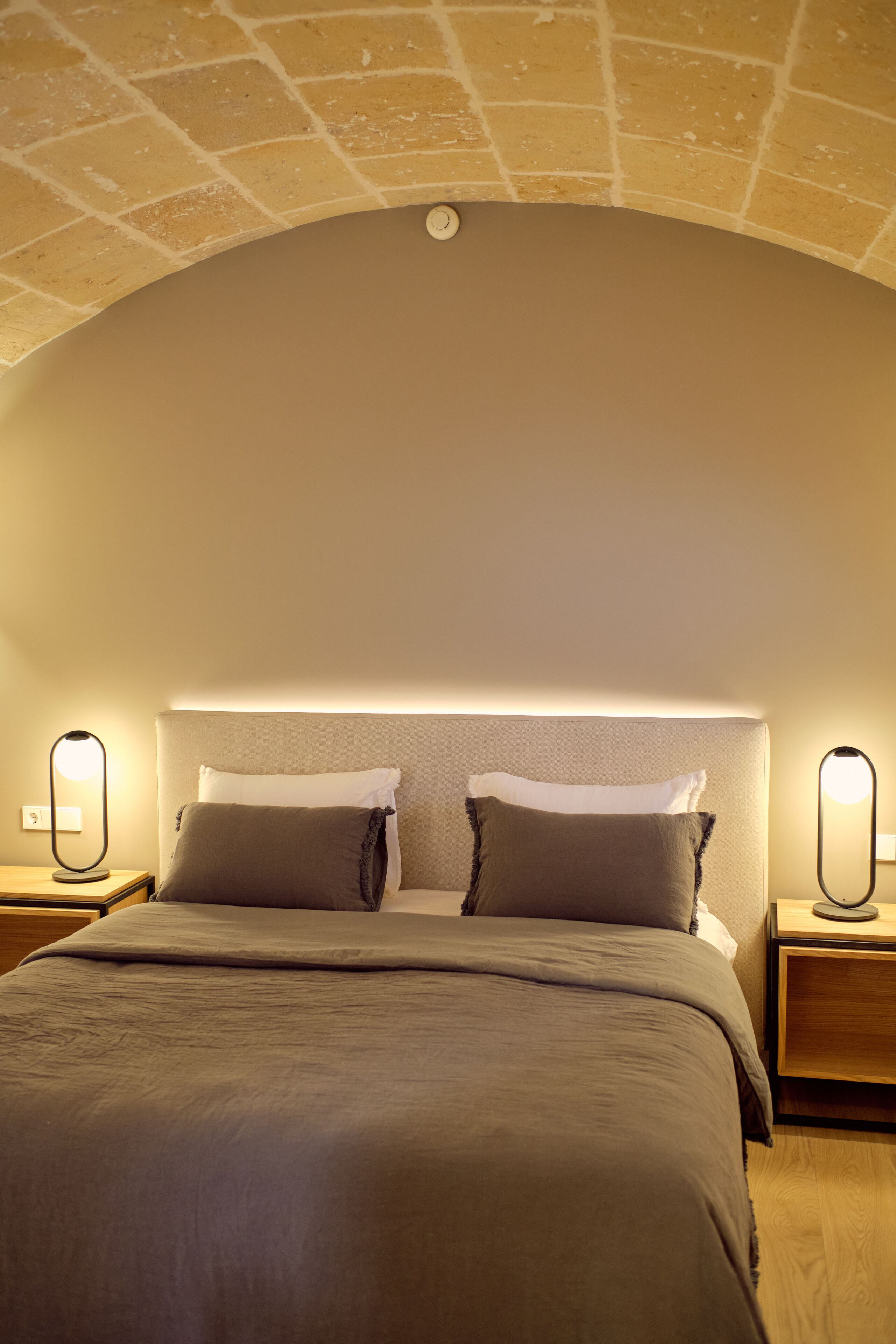 Un dormitorio con una cama grande, dos mesitas de noche con lámparas y un techo curvo.