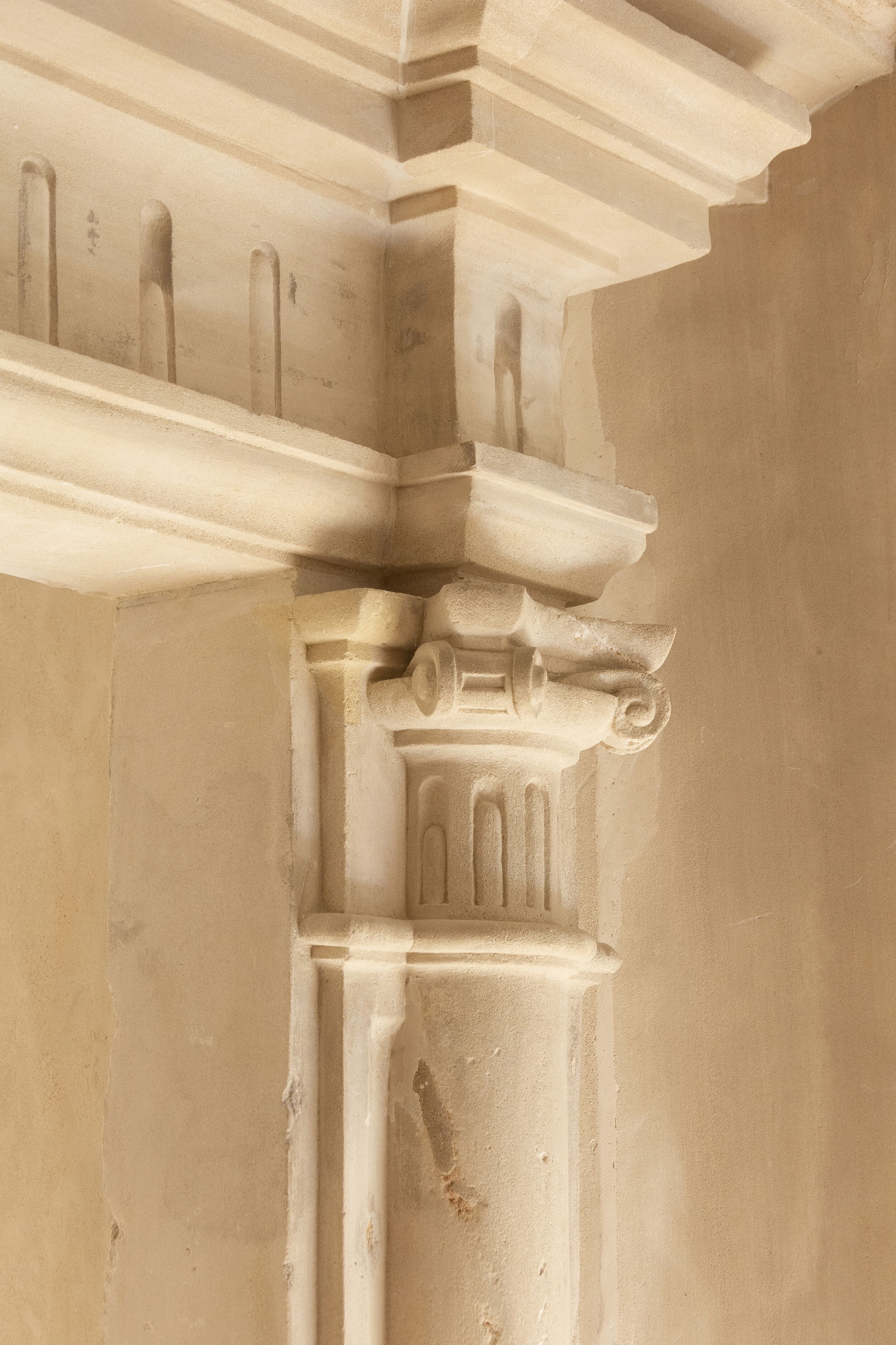 Primer plano de una columna arquitectónica clásica con fustes acanalados y un capitel con volutas.