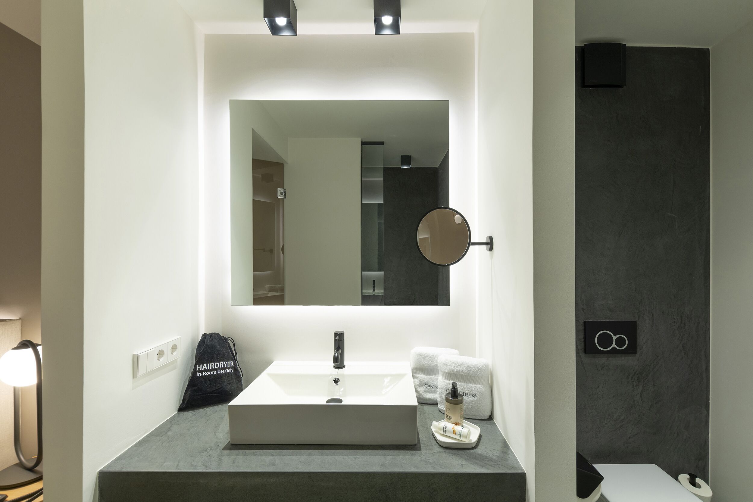 Un baño moderno con un lavamanos rectangular, un espejo grande y un perchero para toallas.