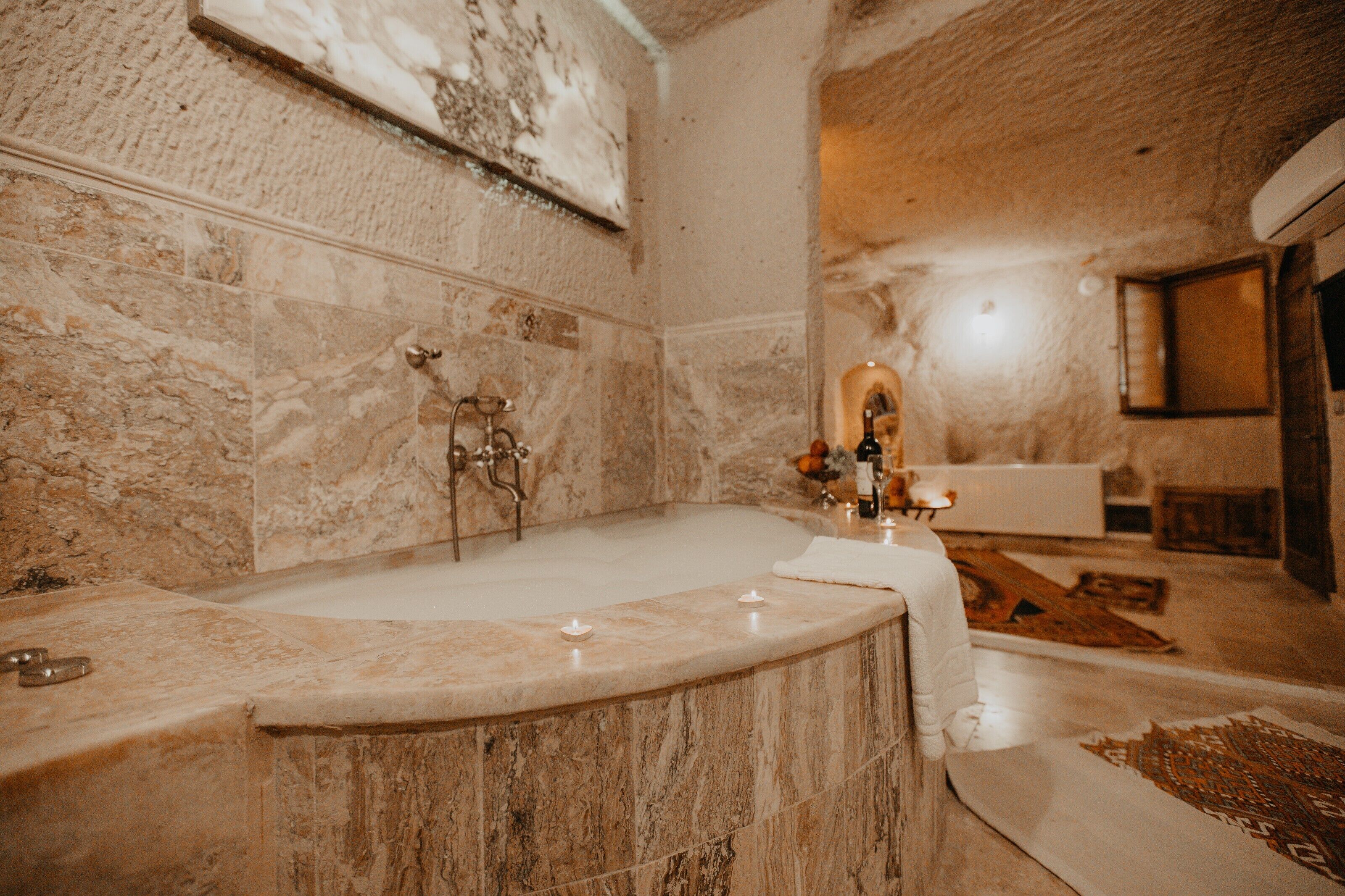 A bathroom with a marble bathtub, a sink, and a mirror.