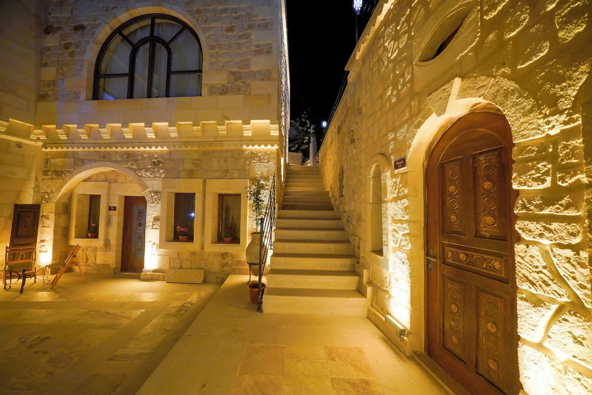 A stone building with a staircase leading to a door, a bench, and a potted plant.