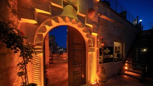 Una entrada ornamentada con una puerta de madera, un jarrón grande con flores y un letrero que dice 