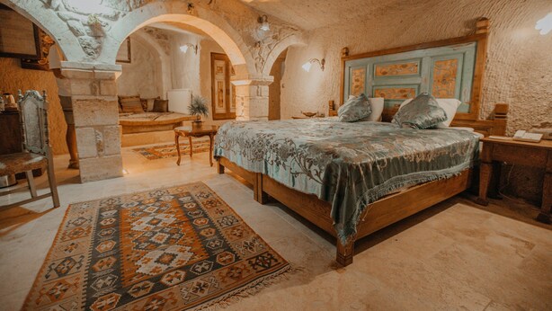 Un dormitorio con una cama grande, cabecera de madera y alfombra estampada.