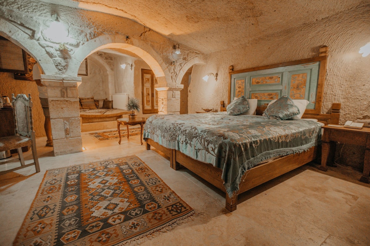 A bedroom with a large bed, a wooden headboard, and a patterned rug.