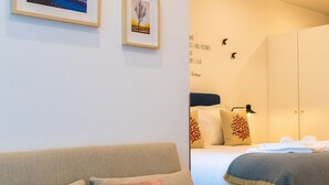 Een moderne slaapkamer met een bed, een slaapbank en lijstjes met foto's aan de muur.