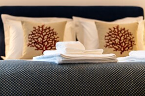 A neatly made bed with folded white towels and decorative pillows with a tree design. - Studio with terrace, 250m from Praia da Granja (São Félix da Marinha)