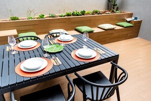 A dining table set with plates, glasses, and cutlery, surrounded by chairs and cushions. - Studio with terrace, 250m from Praia da Granja (São Félix da Marinha)