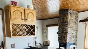 Eine Küche mit Holzausstattung, einer Arbeitsplatte aus Granit und einem Kamin aus Naturstein.