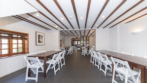 A long dining table with white chairs, wooden beams on the ceiling, and a window with blinds. - Charming 20-bed Self Contained Dwelling in Hook (Hook)
