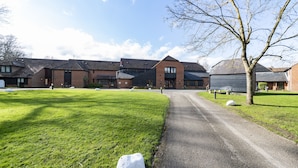 A building with a brick facade, a paved driveway, and a grassy area with a tree. - Charming 20-bed Self Contained Dwelling in Hook (Hook)