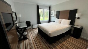 A hotel room with a large bed, a desk with a chair, a TV, and a window with curtains. - Charming 20-bed Self Contained Dwelling in Hook (Hook)