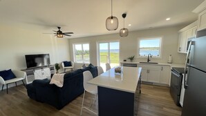 A modern kitchen with a central island, white cabinetry, and a view of the outdoors. - Your Perfect Fall Getaway- Only a 5 Minute Walk From Beautiful North Shore Beach (South Rustico)