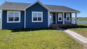 A single-story house with a dark blue exterior, white trim, and a covered porch with outdoor seating. - Your Perfect Fall Getaway- Only a 5 Minute Walk From Beautiful North Shore Beach (South Rustico)