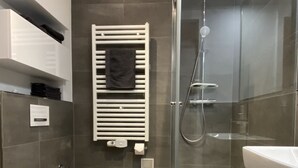 A modern bathroom with a glass-enclosed shower, a white toilet, and a sink.