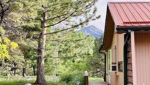 Un bâtiment en bois avec un toit rouge, une terrasse en bois et une montagne en arrière-plan.
