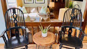 Un salon chaleureux avec une table basse en bois, deux fauteuils noirs, un canapé et un téléviseur.