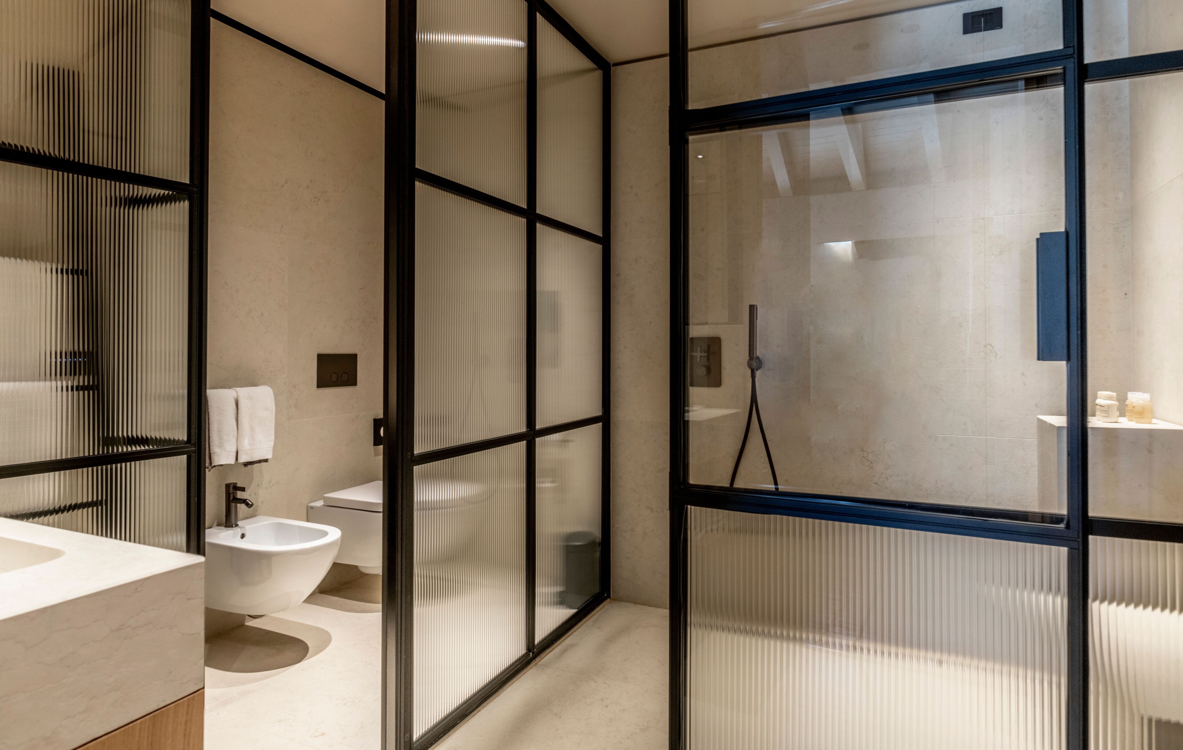 Un baño moderno con bidé, inodoro y un espejo grande.
