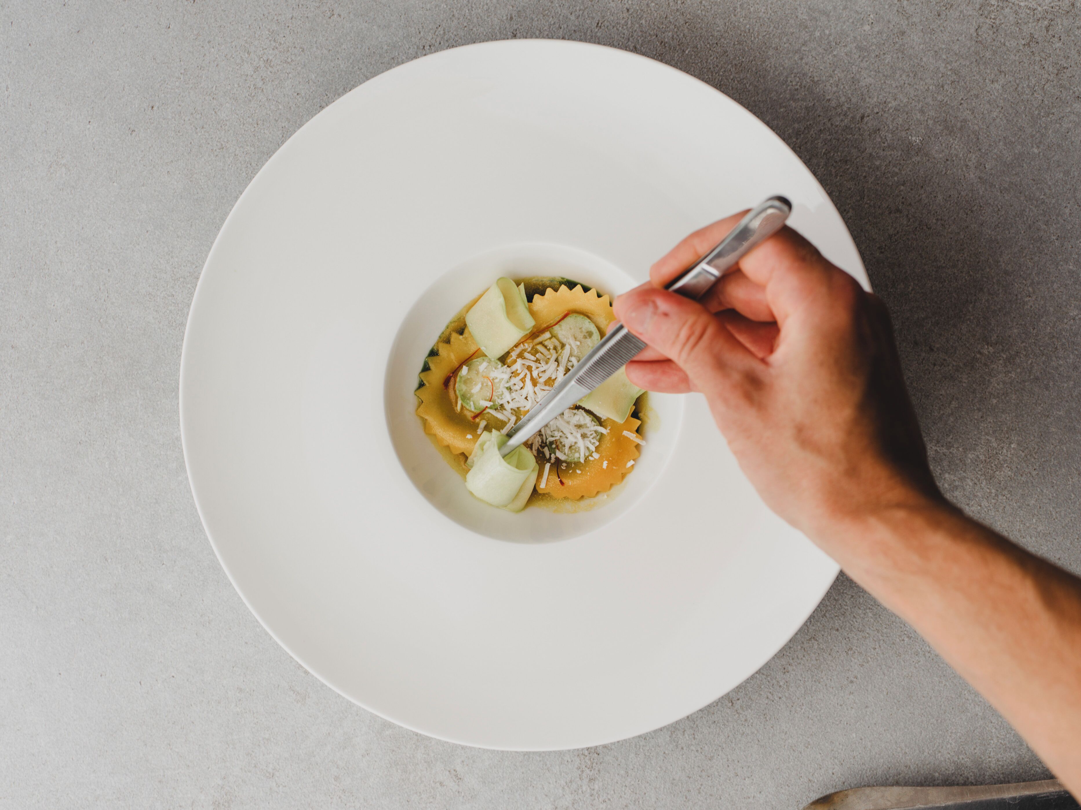 A white plate with pasta and a fork on a textured surface.
