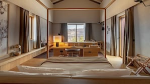 Habitación de hotel con una cama grande, un escritorio con lámpara, una silla y vistas al exterior.