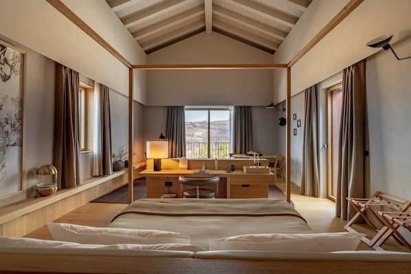 A hotel room with a large bed, a desk with a lamp, a chair, and a view of the outdoors. - Casa di Langa (Cerretto Langhe)