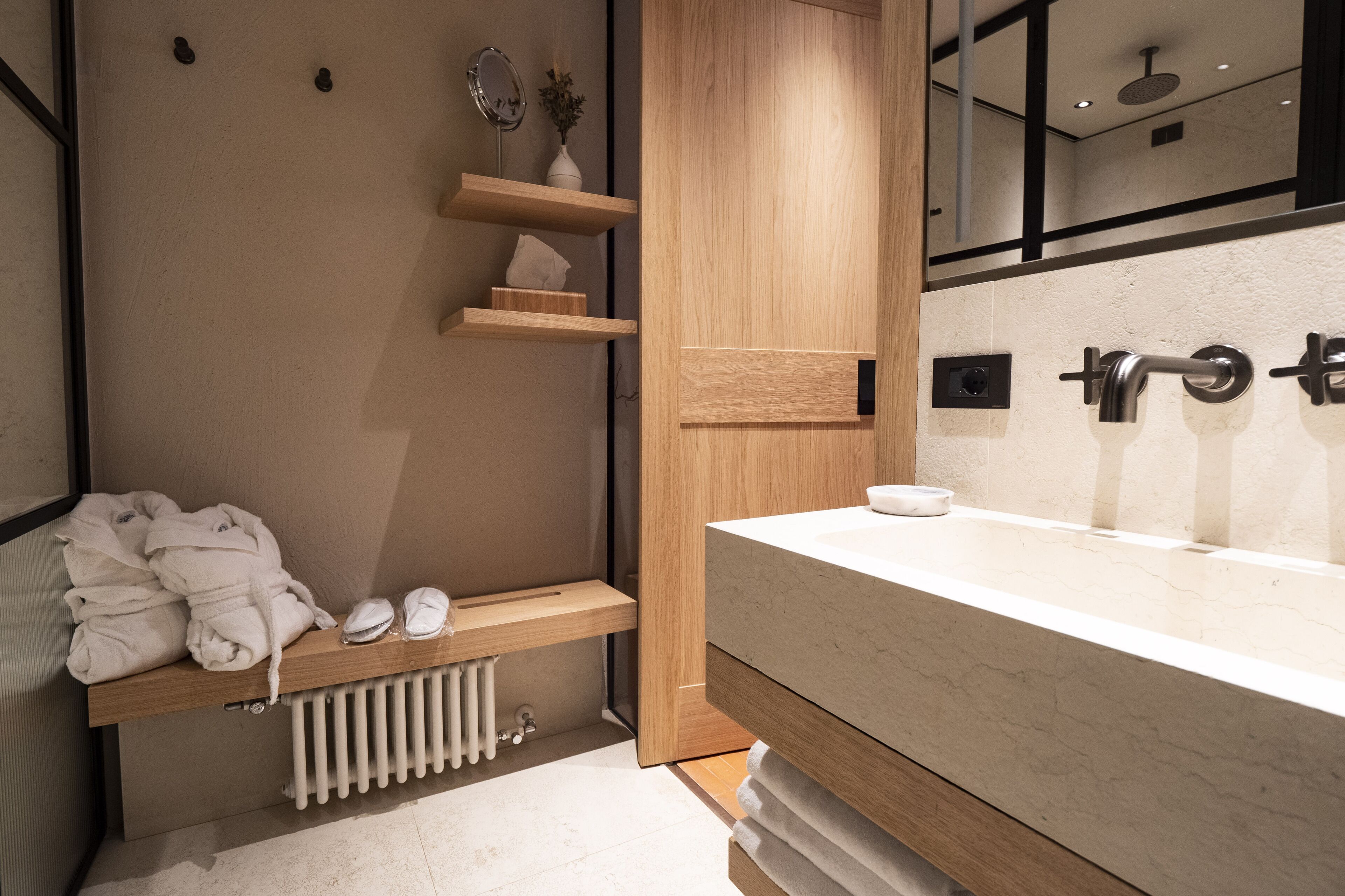Ein modernes Badezimmer mit einem großen Waschbecken, Holzregalen und einem Spiegel.