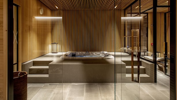 Un baño moderno con una bañera independiente, paneles de madera y un separador de vidrio.