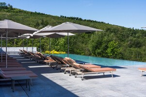 Una piscina al aire libre, sombrillas, sillones reclinables de piscina