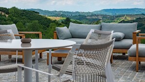 Una terraza con sofá, sillas y una mesa, con vistas a un paisaje pintoresco.