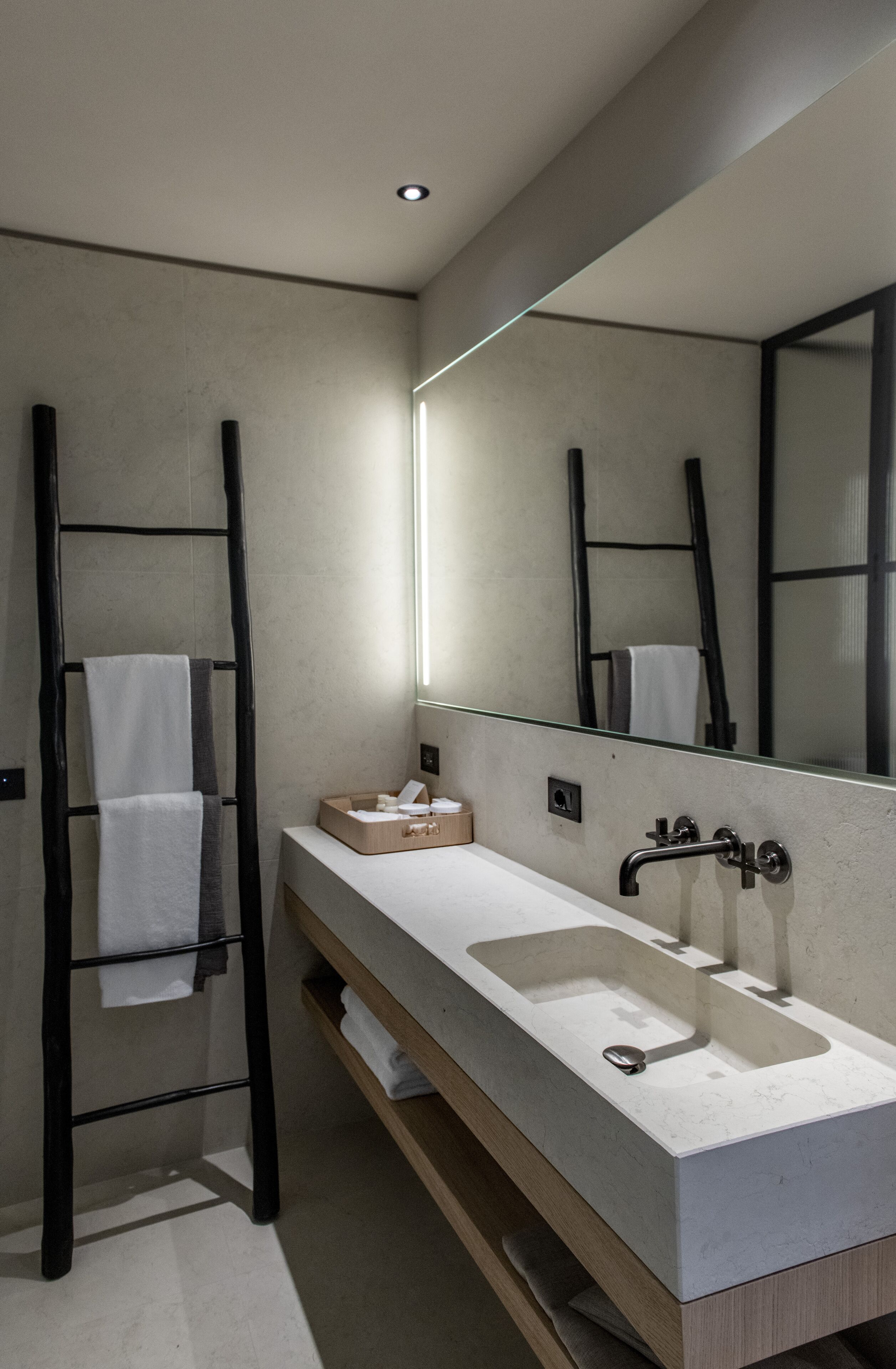 A modern bathroom with a large mirror, a sink, and a towel rack.