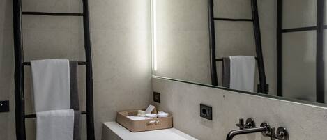 A modern bathroom with a large mirror, a sink, and a towel rack.