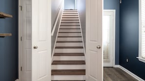A staircase with wooden steps and white walls, leading to an upper floor. - Relax in a Spacious 3 Bedroom + Office- Mud Island/Downtown (Memphis)
