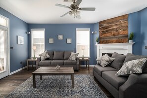 Ein Wohnzimmer mit grauem Sofa, einem Couchtisch und einem Kamin.