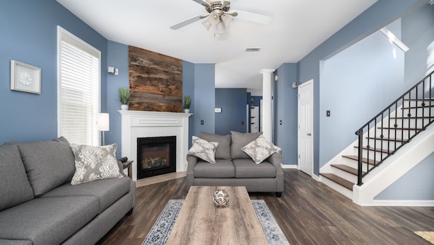 A living room with a fireplace, a gray sofa, a coffee table, and a staircase. - Relax in a Spacious 3 Bedroom + Office- Mud Island/Downtown (Memphis)