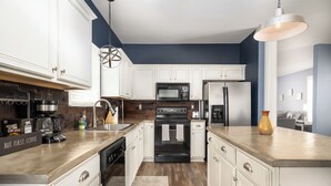 A modern kitchen with white cabinets, a stainless steel refrigerator, a microwave, and a stove. - Relax in a Spacious 3 Bedroom + Office- Mud Island/Downtown (Memphis)