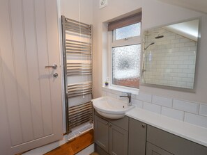 A bathroom with a shower, a sink, and a window with frosted glass. - Millside (Lincoln)