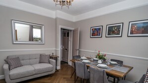 A dining area with a wooden table set for four, a grey sofa, and a mirror on the wall. - Millside (Lincoln)