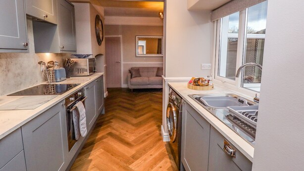 A compact kitchen with grey cabinets, a dishwasher, a sink, and a window. - Millside (Lincoln)